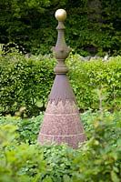 A salvaged cast-iron finial creates focal point in garden. 