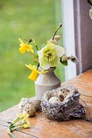 Small spring posy in earthenware bottle with birds nest and eggs. 