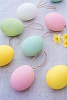 Pastel coloured easter eggs with string on linen background