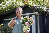 Woman holding a chicken and a hydrangea in a pot