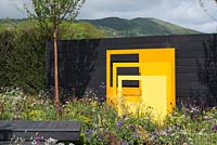 Yellow steel sculptural panels with black fence background - 'Urban Oasis', RHS Malvern Spring Festival, 2018. 