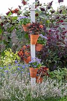 Vertical post planter with colourful planting in modern garden