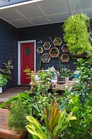 A lush tropical front garden and verandah featuring decorative wall mounted recycled timber planter boxes.