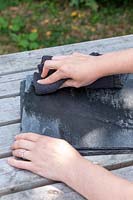 Using a cloth to apply oil to surface of slate tile
