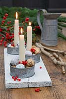Table centrepiece of candle holders featuring painted walnuts and Ilex berries.