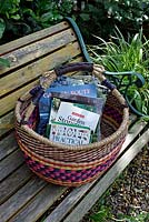 Gardening books in round woven basket on bench. 