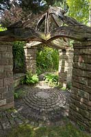 Stone pillared gazebo in the Pinetum with wooden timber roof at York Gate, Leeds, Yorkshire, UK. 