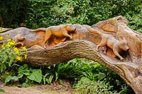 Felled oak carved with a hunting scene on one side, by chainsaw sculptor Matthew Crabb. Abbotsbury Subtropical Gardens, Abbotsbury, Dorset, UK. 