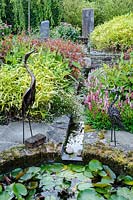 Two metal bird sculptures overlook rill and garden pond, Dipley Mill, Hartley Wintney, Hants, UK. 
