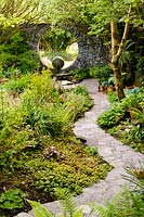Stone path with borders of hostas and ferns and Moon Window. Fanore, Ireland