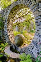 Moon Window in stone wall with cast concrete water feature with shade loving ferns. Fanore, Ireland