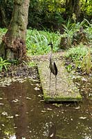 Pond with sculpture of heron with fish in its mouth, Aston Crews, Herefordshire, UK
