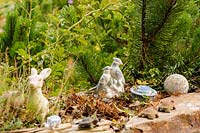 Ceramic animal figures decorate the top of a stone wall in the garden.