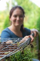 Close up detail of woman using a helical coil spring to secure lid of gabion basket