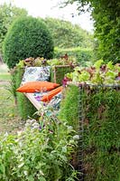 Living gabion bench - metal gabions lined with turf, planted with lettuce plants, with cushions