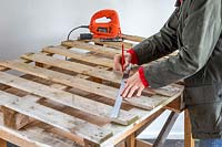 Using a metal ruler and pencil to mark lines on a pallet