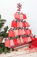 Advent pallet Christmas tree decorated with paper bags filled with festive gifts in a modern festive setting