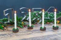 Advent table decoration with large metal number cake tins and tall white candles