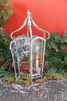 Christmas tree, red chair and lit candle in metal lantern