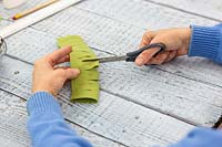 Woman cutting additional slits in felt after unfolding 