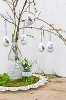 Easter arrangement eggs hanging on branches, Snowdrops and vases decorated with lace