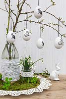 Easter arrangement with eggs hanging on branches, rabbit, Snowdrops and vases decorated with lace