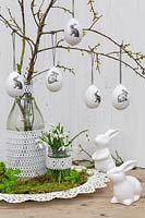 Easter eggs hanging on branches with rabbits, Snowdrops and vases decorated with lace