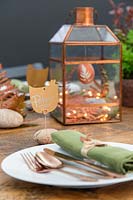 Copper themed Easter display in lantern with place names cards fixed to pebbles with copper wire