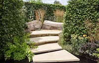 Irregular stone paving and stepping stones over water feature with Carpinus betulus - hornbeam hedges. RHS Watch This Space Garden, Hampton Court Flower Show, 2017