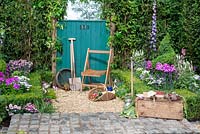 Chair next to a green garden gate with tools, borders with clipped Buxus hedging and topiary, Phlox, Delphinium, Lavandula and Achillea - 130 Years of Port Sunlight, The Garden Village, RHS Tatton Park Flower Show 2018