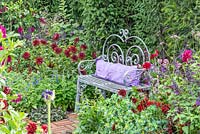 Decorative metal bench surrounded by borders filled with Dahlia 'Admiral Rawlings', Dahlia 'Arabian Mystery', Verbena bonariensis, Salvia 'Amistad' and Salvia patens - The Flowers of Arley, RHS Tatton Park Flower Show 2018