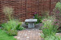 Willow woven fence and water feature, gravel planting of Stipa tenuissima, Scabiosa 'Butterfly Blue', Achillea milliefolium 'Cerise Queen' and oak and concrete setts - Raised by Rivers, RHS Tatton Park Flower Show 2018