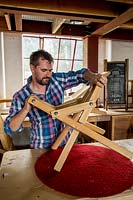 Chris Punch, garden furniture designer in workshop assembling a footstool.