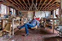 Chris Punch, garden furniture designer in his workshop, with the range of chairs he produces