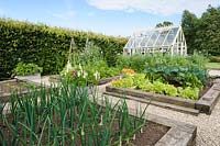 Formal vegetable garden with railway sleeper edged raised beds and a traditional greenhouse.