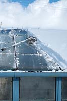 Removing snow from greenhouse roof using a long-handled broom