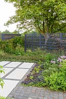 Porcelain paving and granite cobbles with trellis fencing and Walnut tree