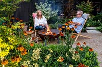 Owners Claire and Sean McHugh sitting in garden with Helenium 'Moerheim Beauty'and Achillea
