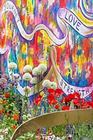The Supershoes, Laced with Hope Garden, a partnership with Frosts - Metal ribbon sculpture against colourful graffiti wall and mixed planting - RHS Chelsea Flower Show, 2018 - Sponsor: Frosts Garden Centres