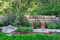 The Warner Edwards Garden, copper seats and fire-pit, backed by a drystone wall and mixed planting - RHS Chelsea Flower Show, 2018