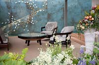 The Morgan Stanley Garden for the NSPCC - Seating in garden room with wall decoration reflected in table top - Sponsor: Morgan Stanley - RHS Chelsea Flower Show 2018