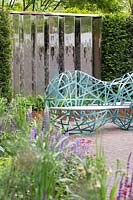 Blue sculptural benches surrounded by metal screens and perennial planting - The David Harber and Savills garden, Sponsor: David Harber and Savills. RHS Chelsea Flower Show, 2018.