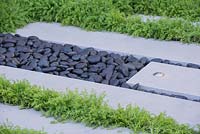 Chamaemelum nobile 'Treneague' planted in between paving slabs and black pebbles - The LG Eco-City Garden - Sponsor: LG Electronics - RHS Chelsea Flower Show 2018