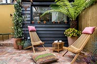 Pair of wooden garden chairs in London patio garden. 
