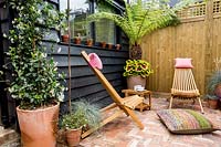 London patio garden with pergola, wooden garden office, mixed planting and wooden garden chairs
