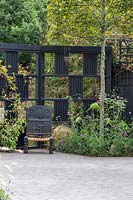 Black trellis room divider and decorative chair and mixed planting
