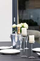 Table set with white roses, candles and champagne in cooler. 