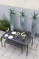 View from above of modern metal dining table with tall planters in background