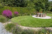 Modern suburban garden with circular patio inset in an oval lawn. 