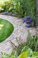 Curved brick path with shady planting of Ferns and Hosta - floral arrangement of Hydrangea and Eucalyptus
